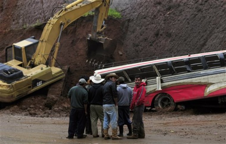 People stand in front of a bus partially covered by a landslide caused by heavy rains on the Pan-American highway at Tecpan, Guatemala, on Saturday. 